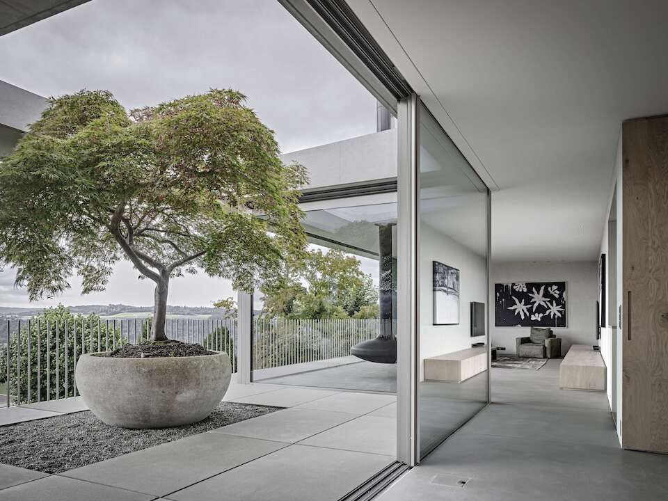 Une maison en béton au design minimaliste avec de grandes fenêtres coulissantes