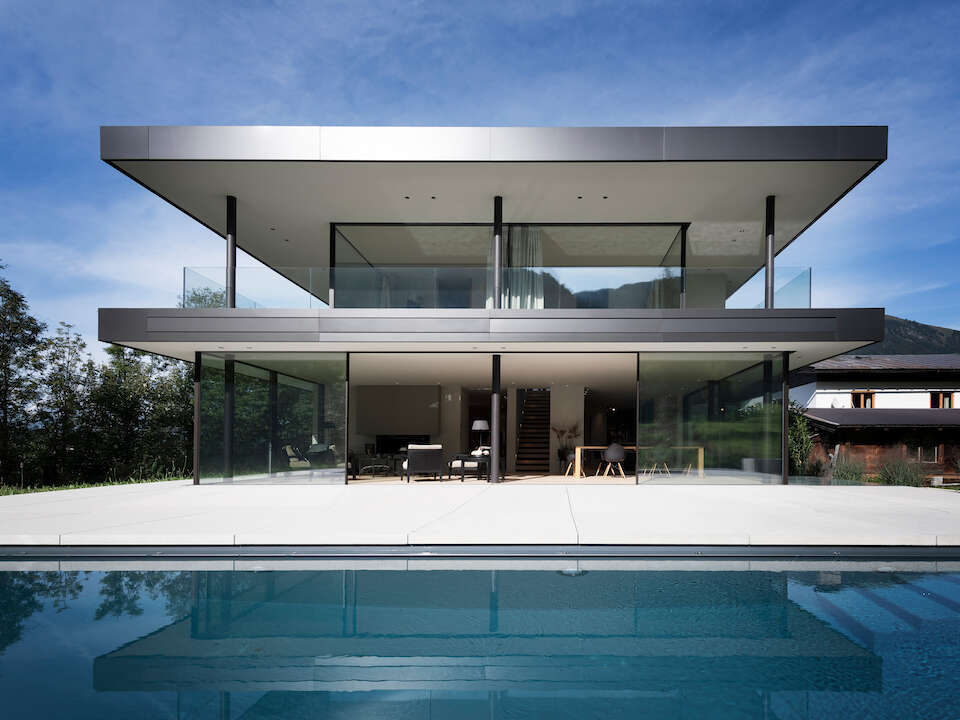 Une villa moderne avec piscine et des murs composés de fenêtres coulissantes se fondant dans le sol