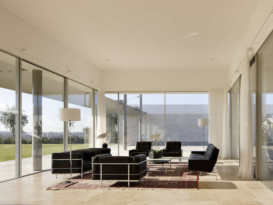 Salon avec fenêtres coulissantes sans cadre d’angle et fauteuils Le Corbusier